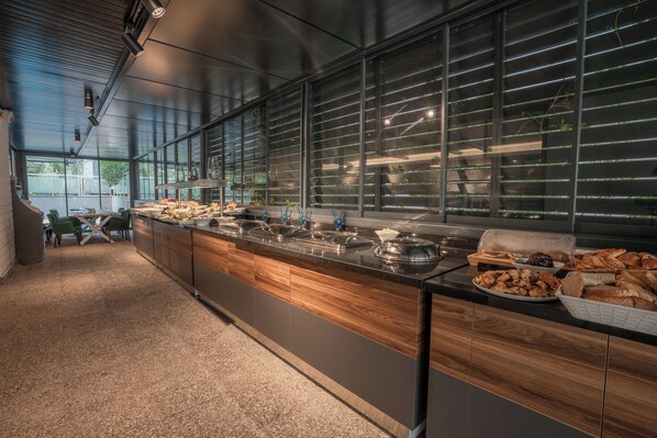 Cocina moderna con una encimera larga, diversos alimentos y vistas al exterior.
