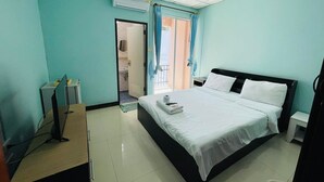 A hotel room with a bed, a desk, an air conditioner, and a bathroom visible through an open door.
