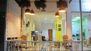 An interior space with hanging plants, pendant lighting, and a seating area with chairs and tables.