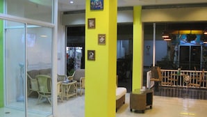 A modern interior with glass walls, a bright yellow pillar, wicker furniture, and a small table.
