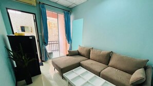 A living room with a sofa, a coffee table, a TV stand, and a sliding door leading to a balcony.