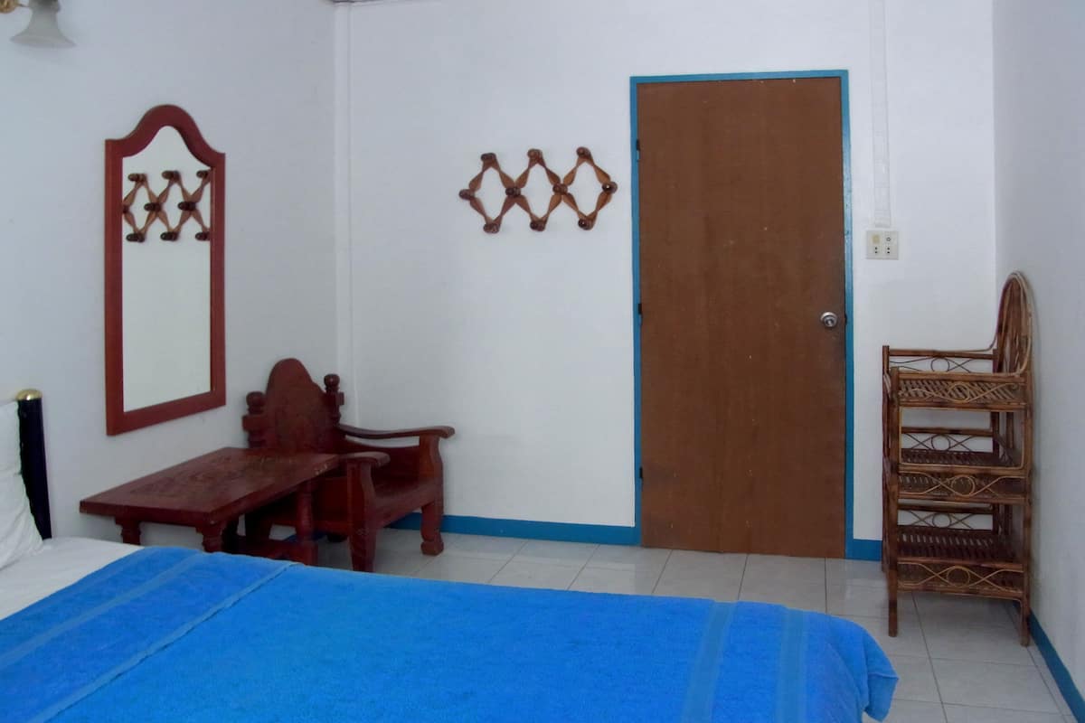 Un dormitorio con una cama, un escritorio de madera, una silla, un espejo y una puerta.