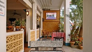 A cozy outdoor seating area with a checkered tablecloth, wicker chairs, and potted plants.