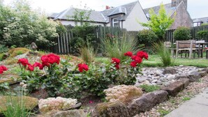 A garden with red roses, a stone pathway, and a wooden fence. - Middleton House (Auchterarder)