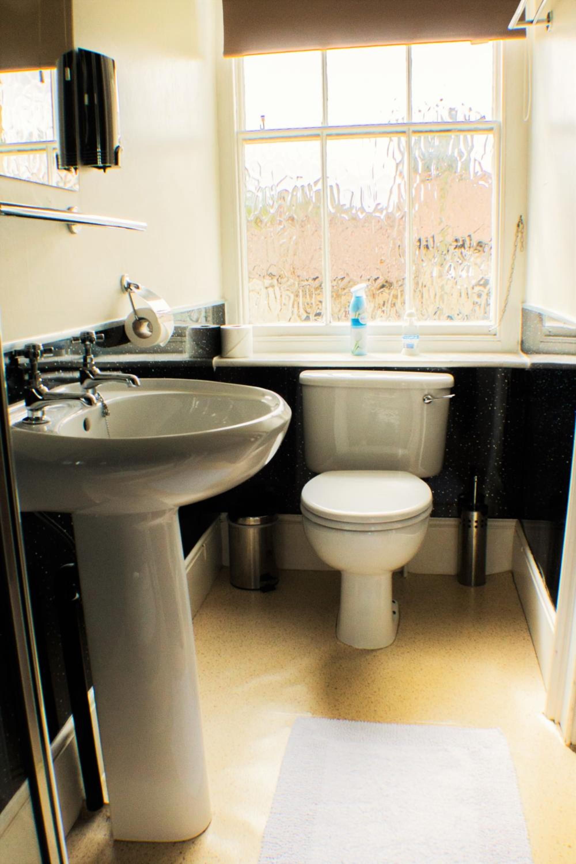 Un baño con lavamanos, inodoro y ventana.