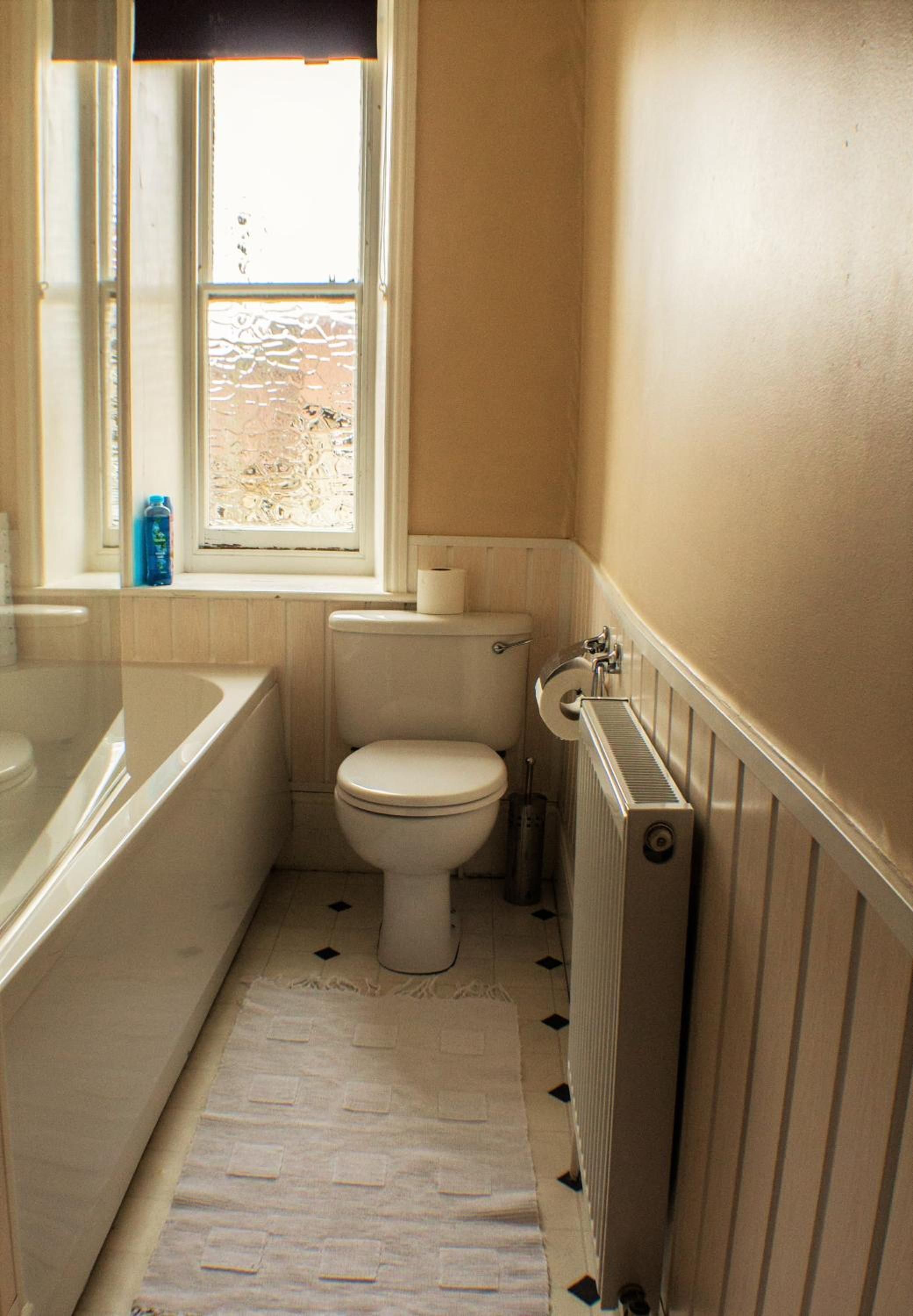 Un bagno piccolo con il water, una finestra e un termosifone.