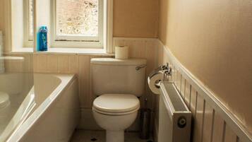 A small bathroom with a toilet, a window, and a radiator.