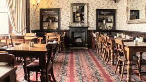 A traditional dining room with wooden tables and chairs, a patterned carpet, and a fireplace. - The Royal Oak Hotel (York)