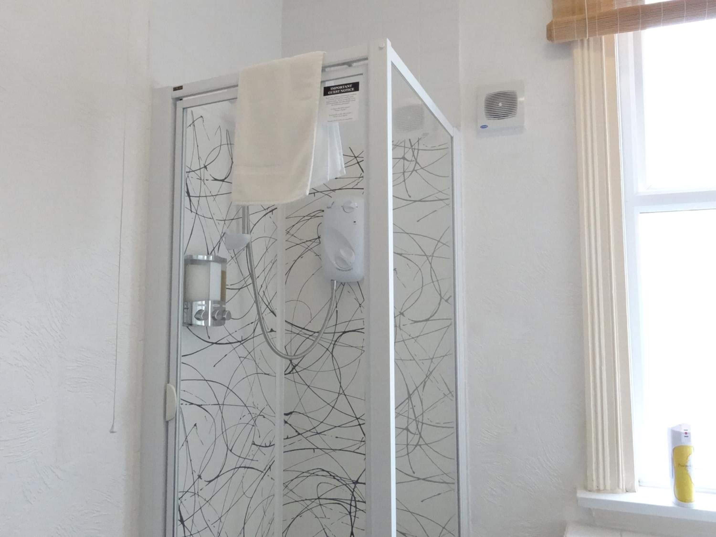 Eine Dusche mit Glastür und einem daran hängenden Handtuch.