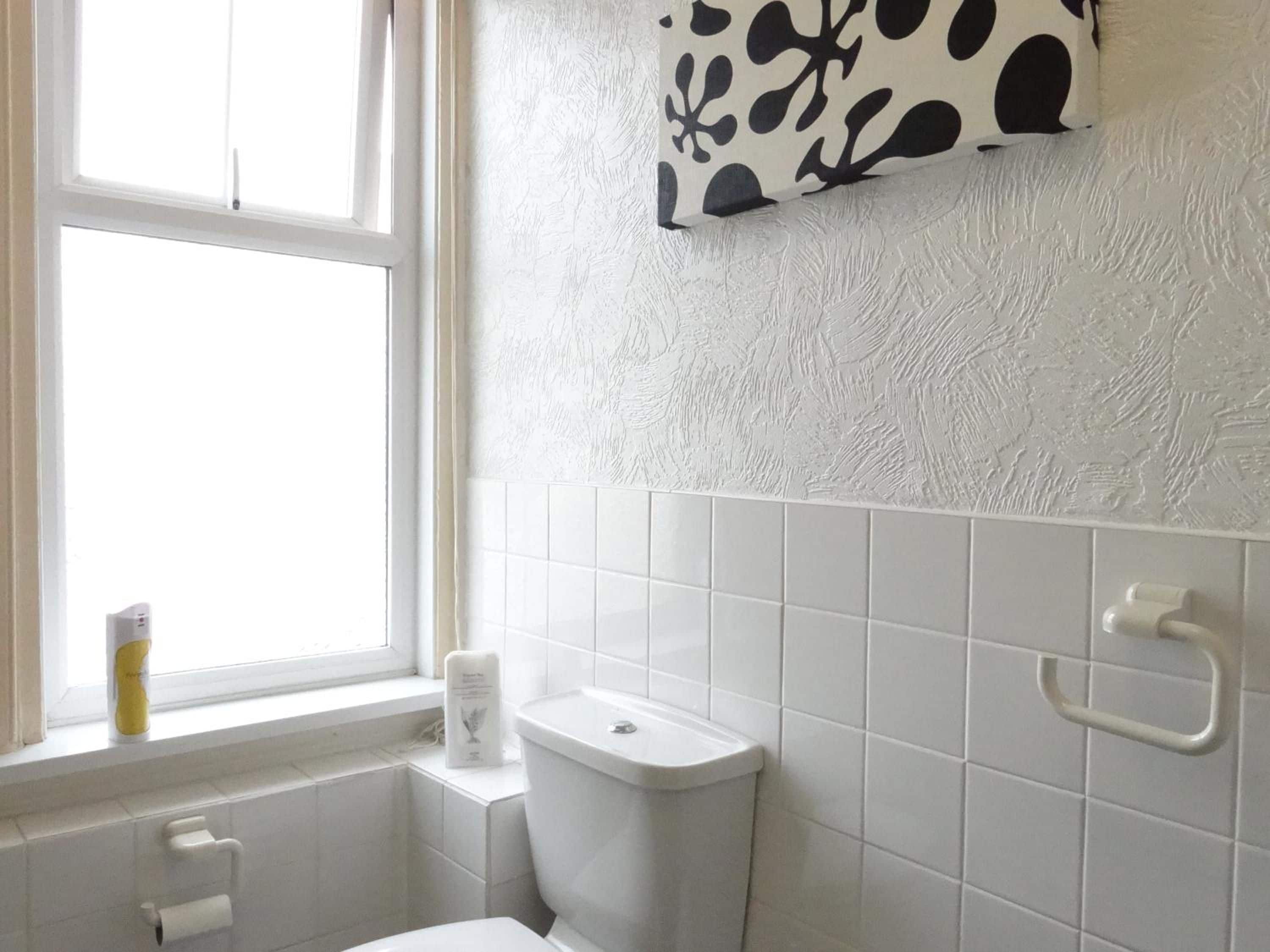 A bathroom with a toilet, a sink, a window, and a wall-mounted towel rack.