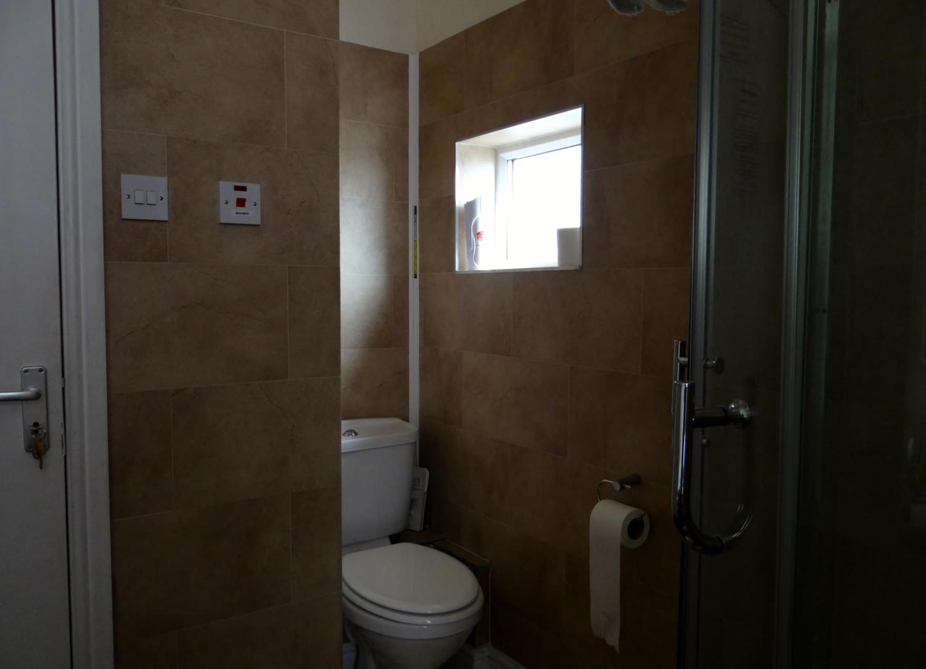 A bathroom with a toilet, a shower, and a window.