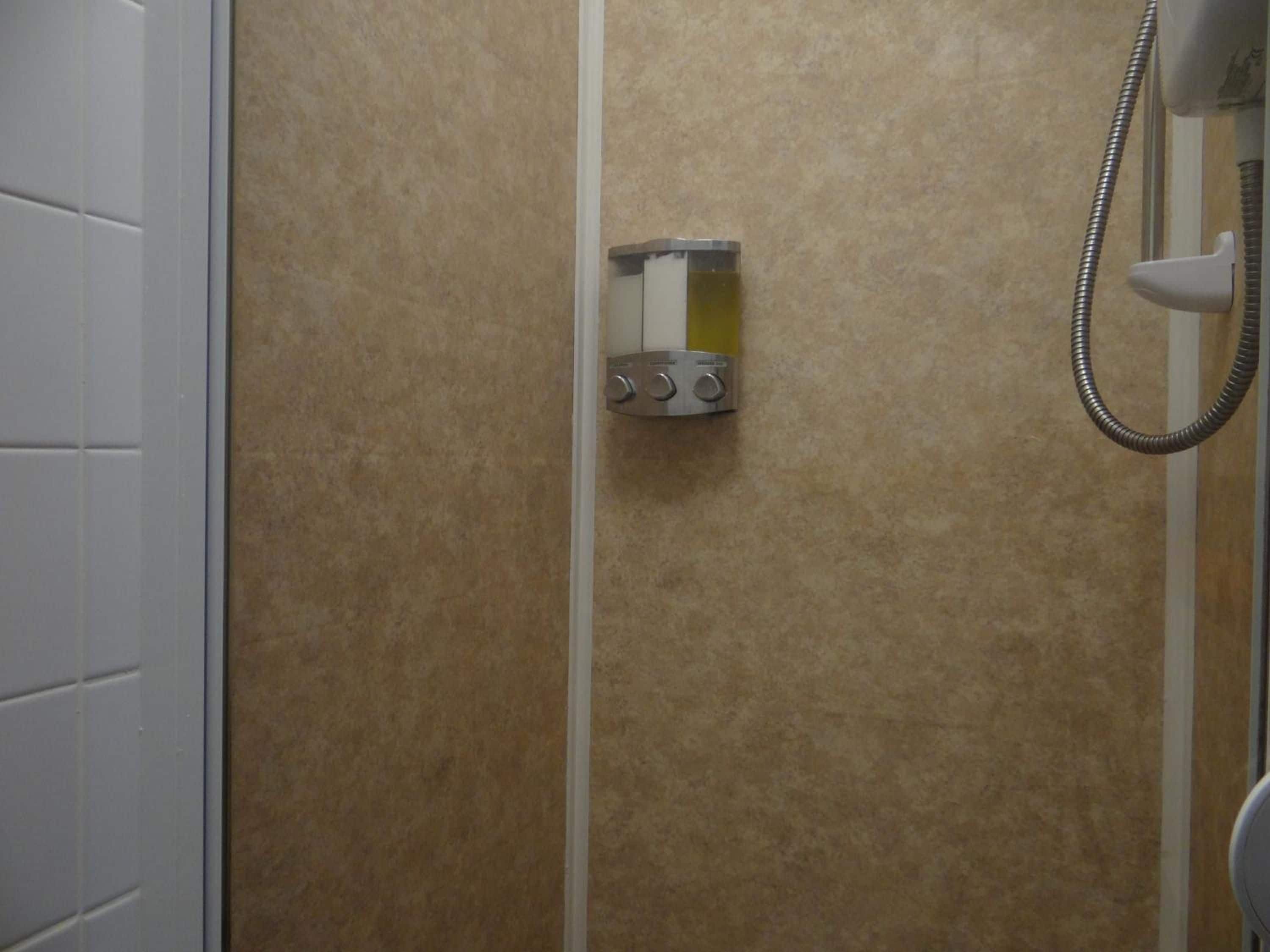 Eine Dusche mit Duschbrause und Bedienfeld mit zwei Drehgriffen.