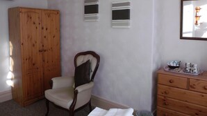 A bedroom with a wooden wardrobe, a chair, a dresser, and a mirror on the wall. - The Jasmine Guest House (Bridlington)