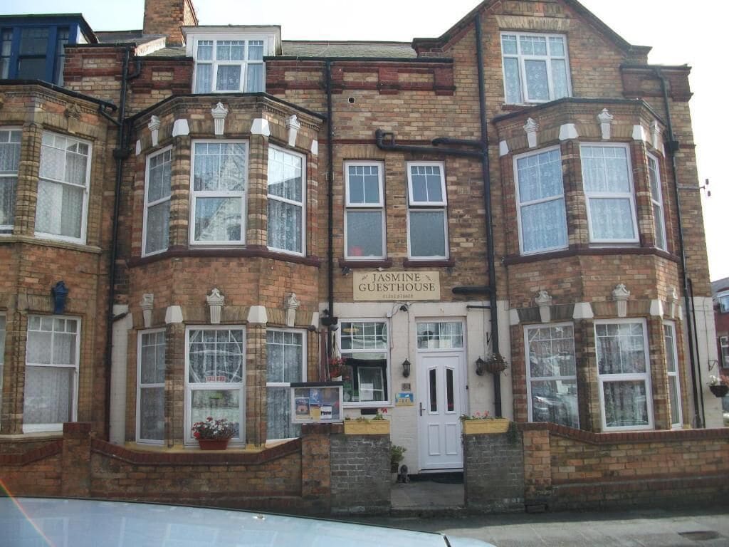 A two-story building with a sign reading 'Jasmine Guesthouse.'