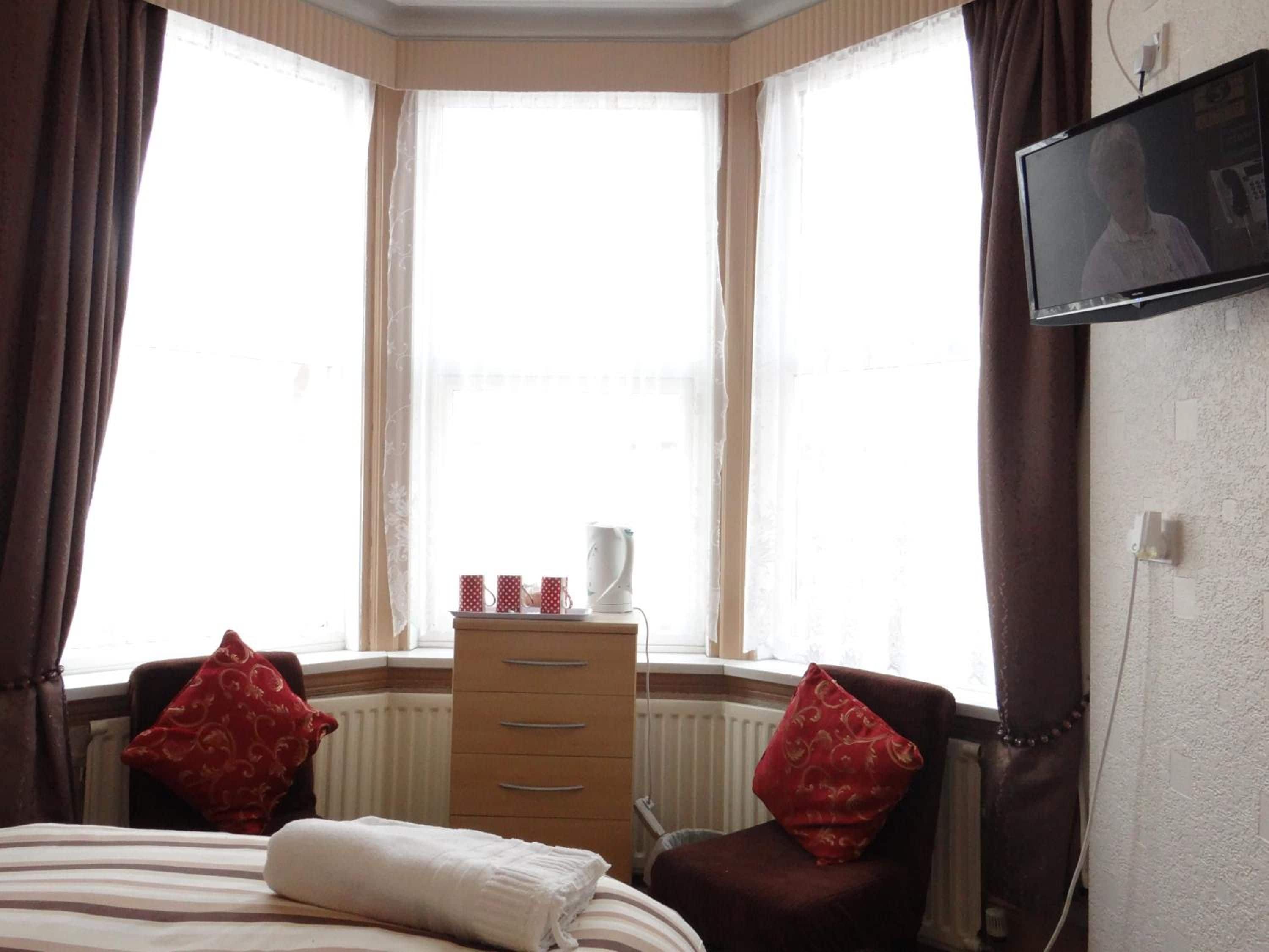 A hotel room with a bed, a dresser, a radiator, and a television on the wall.