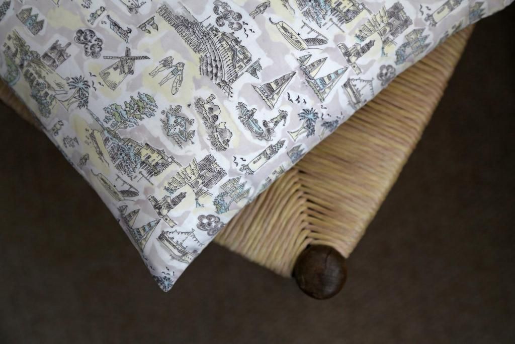 A bed with a patterned bedspread featuring various architectural and cultural illustrations.