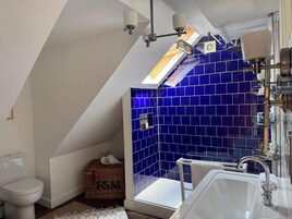 Un baño con tragaluz, bañera y zona de ducha con azulejos azules.