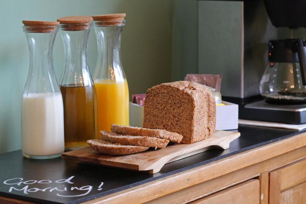 Ein Frühstückstisch mit Brot, Milch und Orangensaft auf einer Küchenarbeitsfläche.