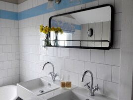 Un bagno con due lavandini, uno specchio e uno scaffale con fiori.