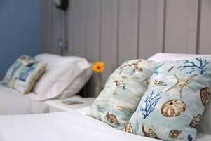 Una cama con ropa de cama y almohadas con diseño marino.