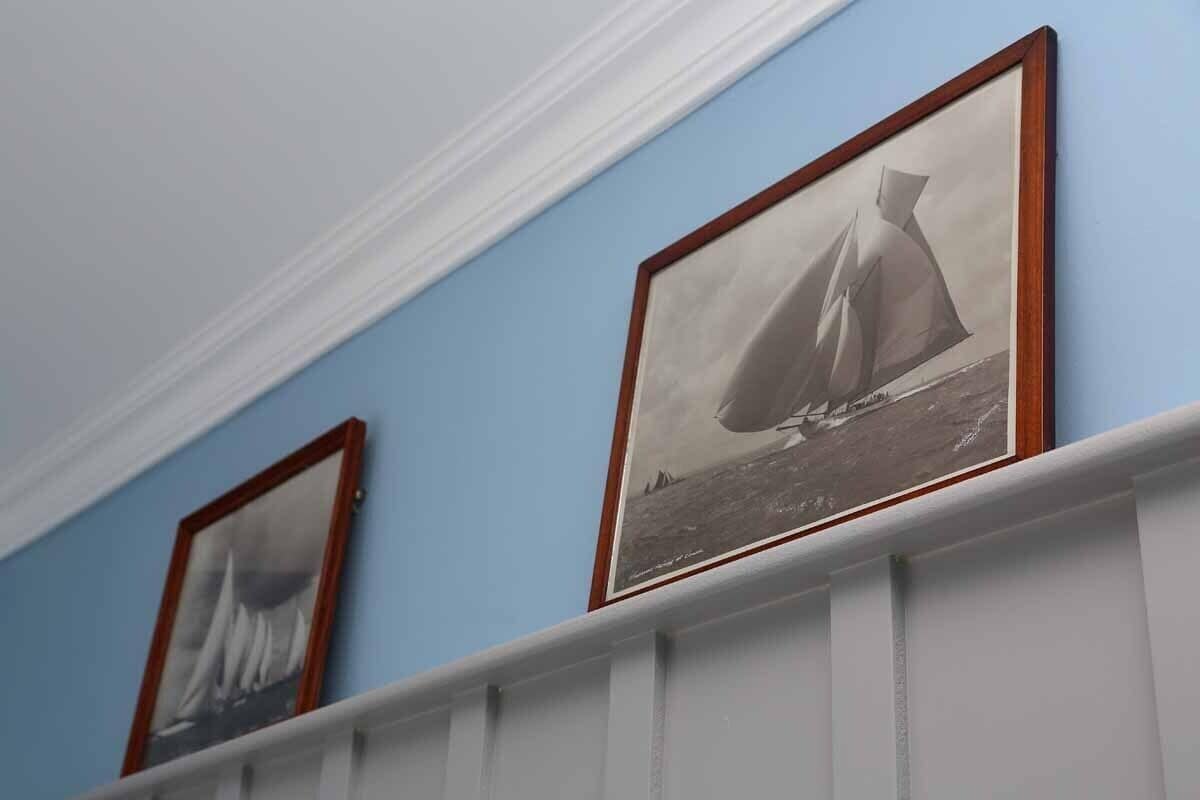 A hallway with framed black and white photographs of sailboats on the wall.