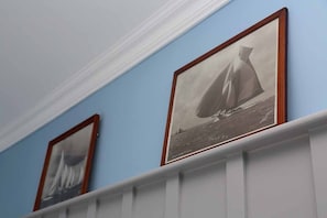 A hallway with framed black and white photographs of sailboats on the wall. - Holly Tree House (Cowes)