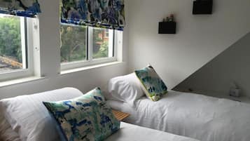 Ein Schlafzimmer mit zwei Betten, einem Fenster mit Blick und einer kleinen Ablage mit Flaschen.
