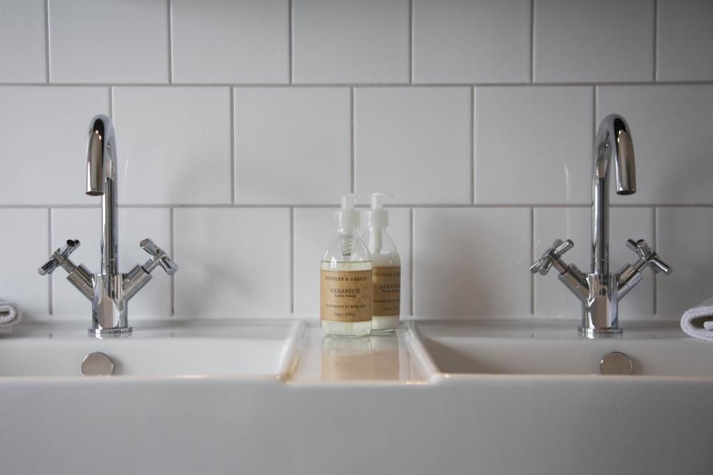 Un baño con dos grifos cromados y un lavabo blanco.