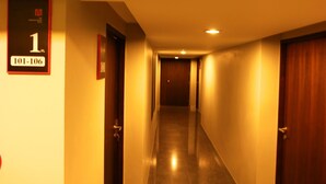 Corredor de hotel com portas numeradas de 101 a 106, uma placa indicando a sala 1 e uma porta de madeira à direita.