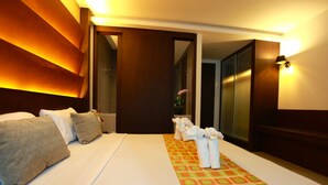 Quarto de hotel com cama, almofadas, porta-toalhas e espelho.