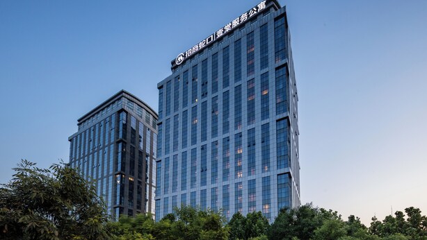 Un edificio moderno de gran altura con fachada de vidrio y un letrero llamativo en la parte superior.