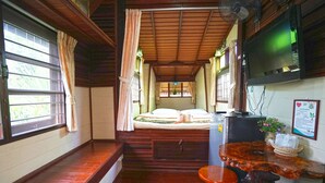A room with a bed, a TV, a wooden table, and a window with curtains. - Raisongrao Resort (Khao Kho)