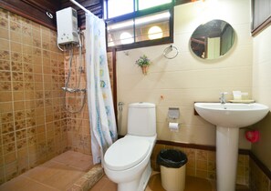 Un baño con inodoro, ducha, lavamanos y un cubo de basura.