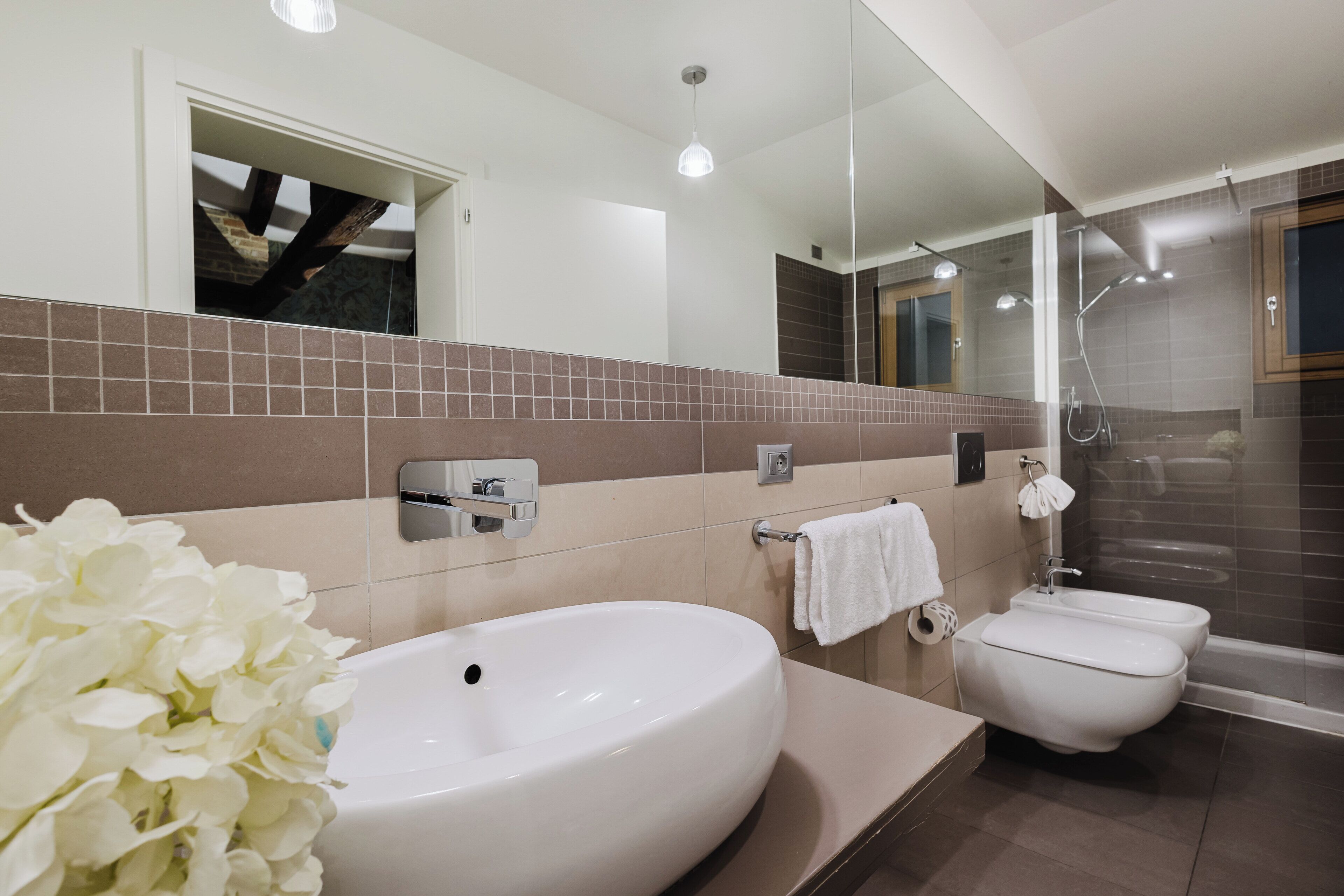 A modern bathroom with a large white sink, a toilet, and a shower area.