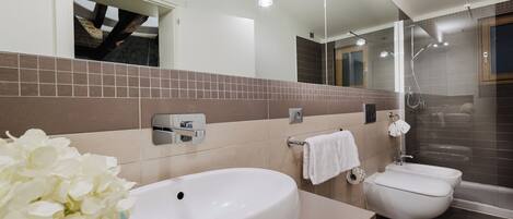 A modern bathroom with a large white sink, a toilet, and a shower area.