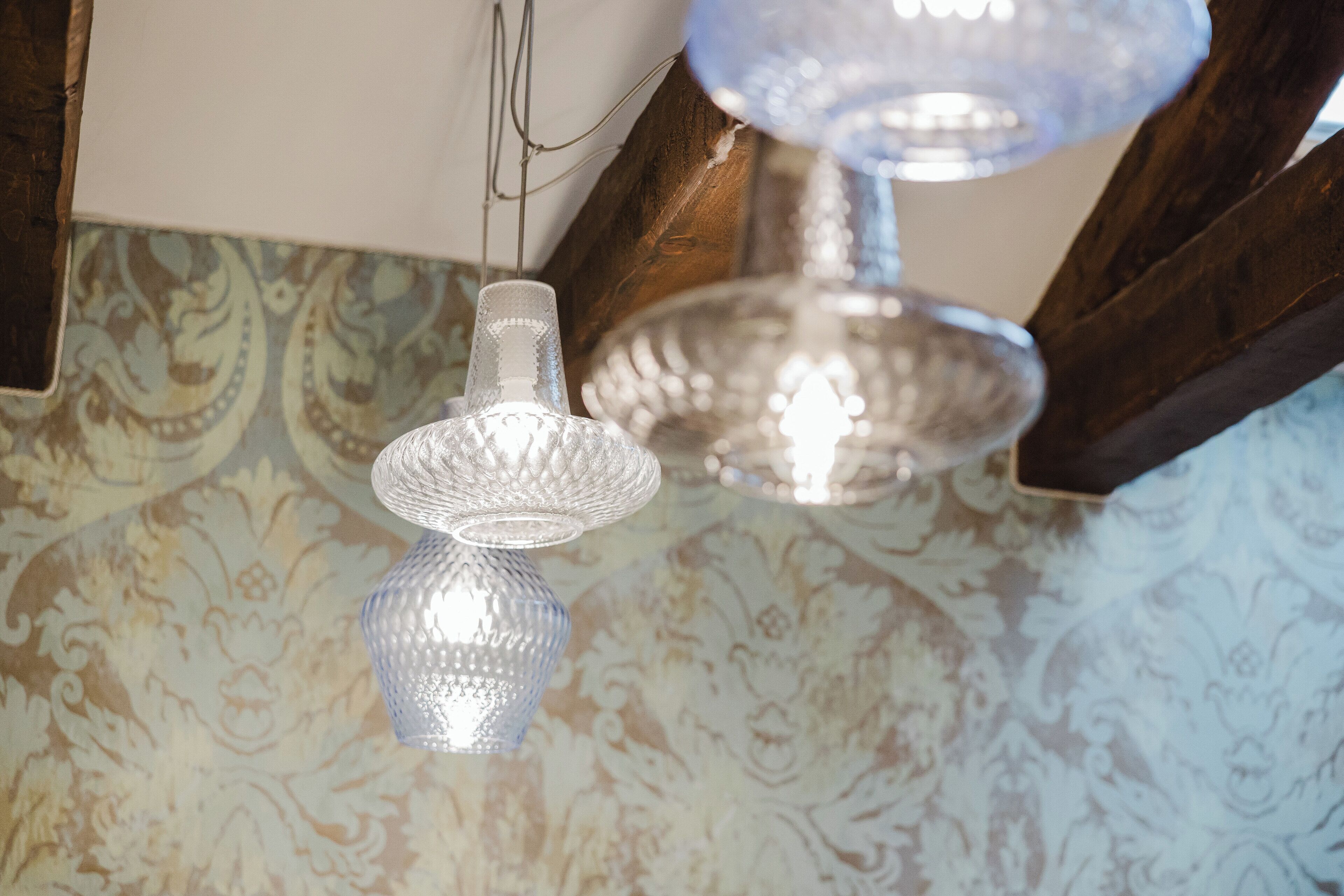 Een plafond met decoratief behang en twee hanglampen met een bijzondere textuur.