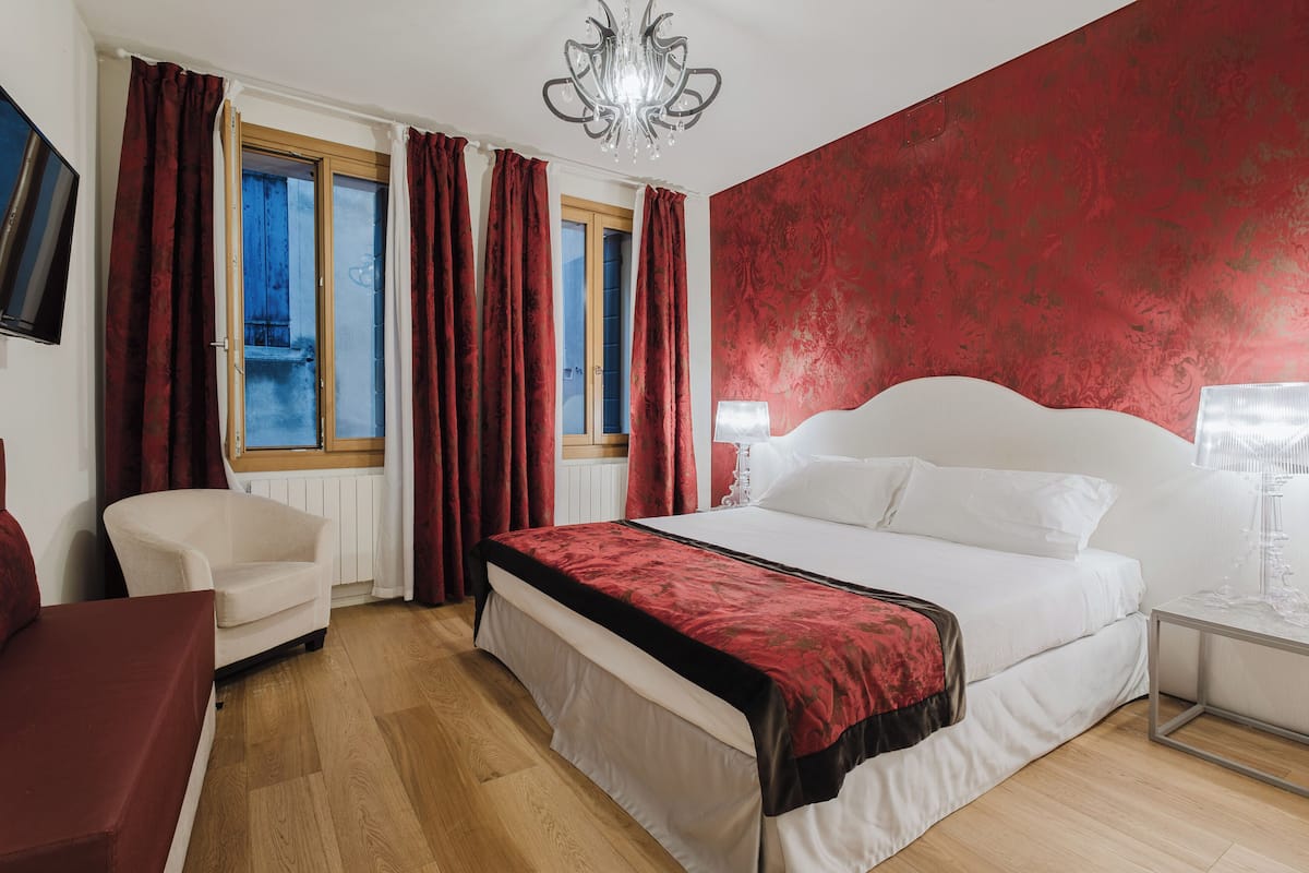 Una camera da letto con un letto, una sedia, un comodino e una finestra con tende.