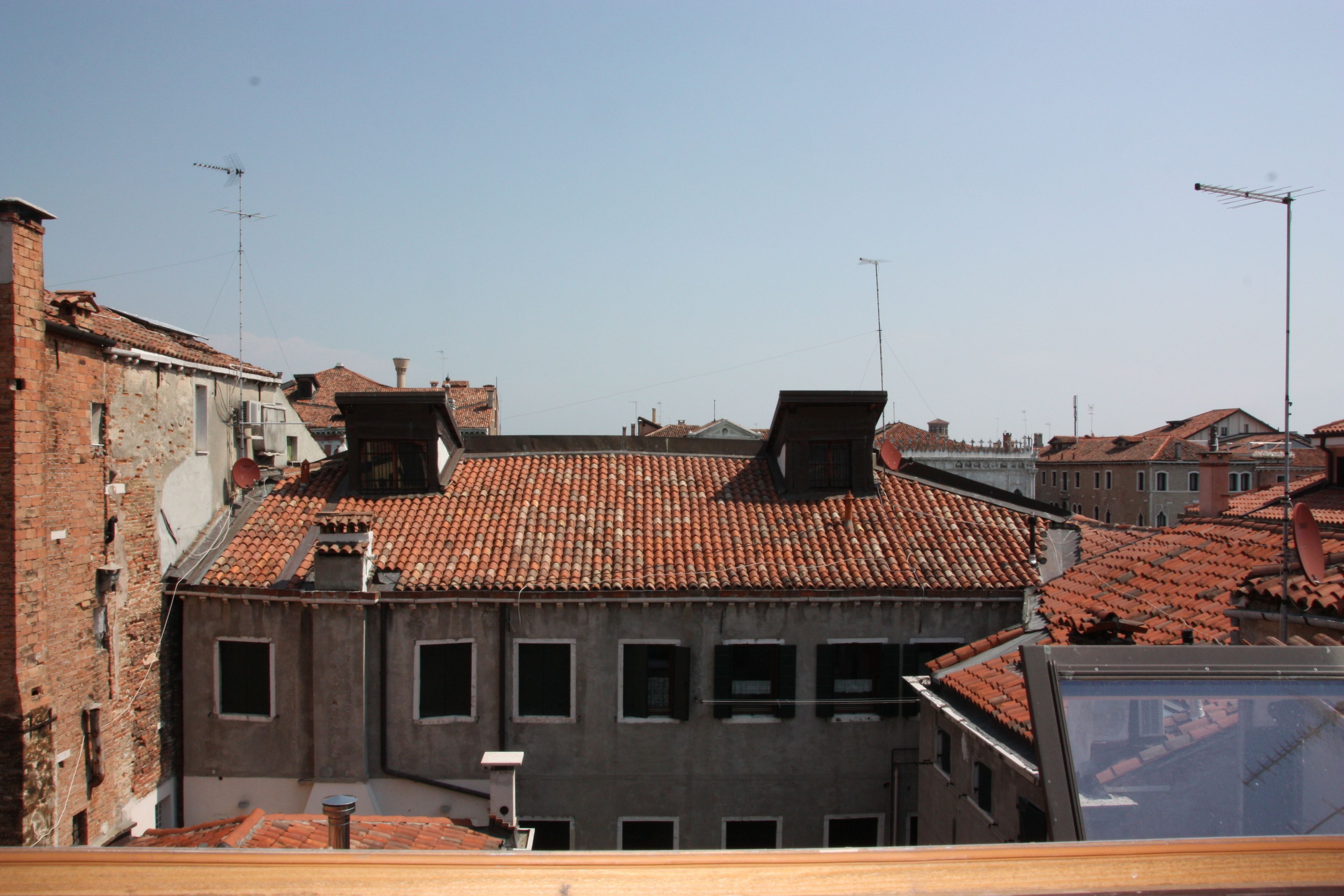 A building with a red-tiled roof, multiple windows, and a chimney.