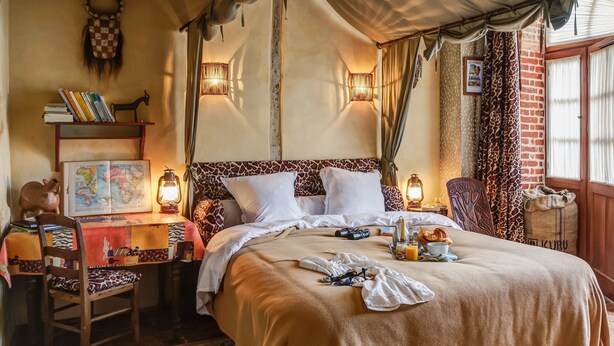 Une chambre confortable avec un grand lit, une carte posée sur une table de chevet, une bibliothèque et une décoration rustique.