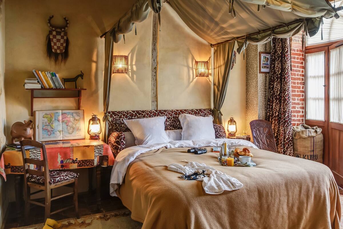 Een gezellige slaapkamer met een groot bed, een kaart op een bijzettafeltje, een boekenkast en een rustieke inrichting.