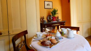 Une table de petit-déjeuner dressée avec une assiette de nourriture, une tasse, un pichet et un vase rempli de fleurs.