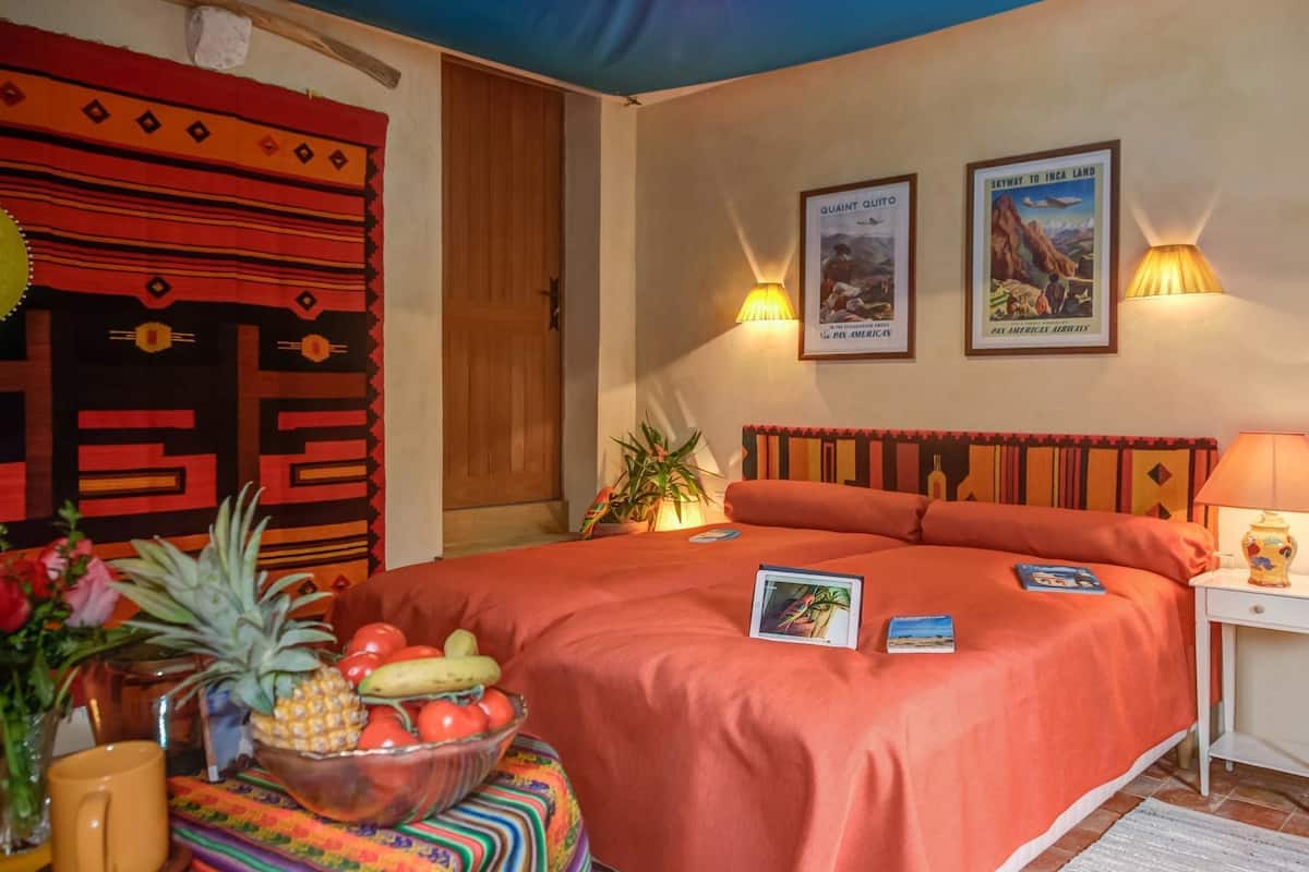 Hotelkamer met een groot bed, twee wandlampen, een houten hoofdeinde en een klein nachtkastje met een lamp.