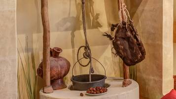 A rustic interior with a wooden shelf holding a pot, a hanging bag, and a book.