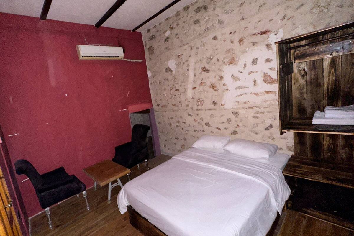 A room with a bed, a small table, a chair, and a wardrobe.