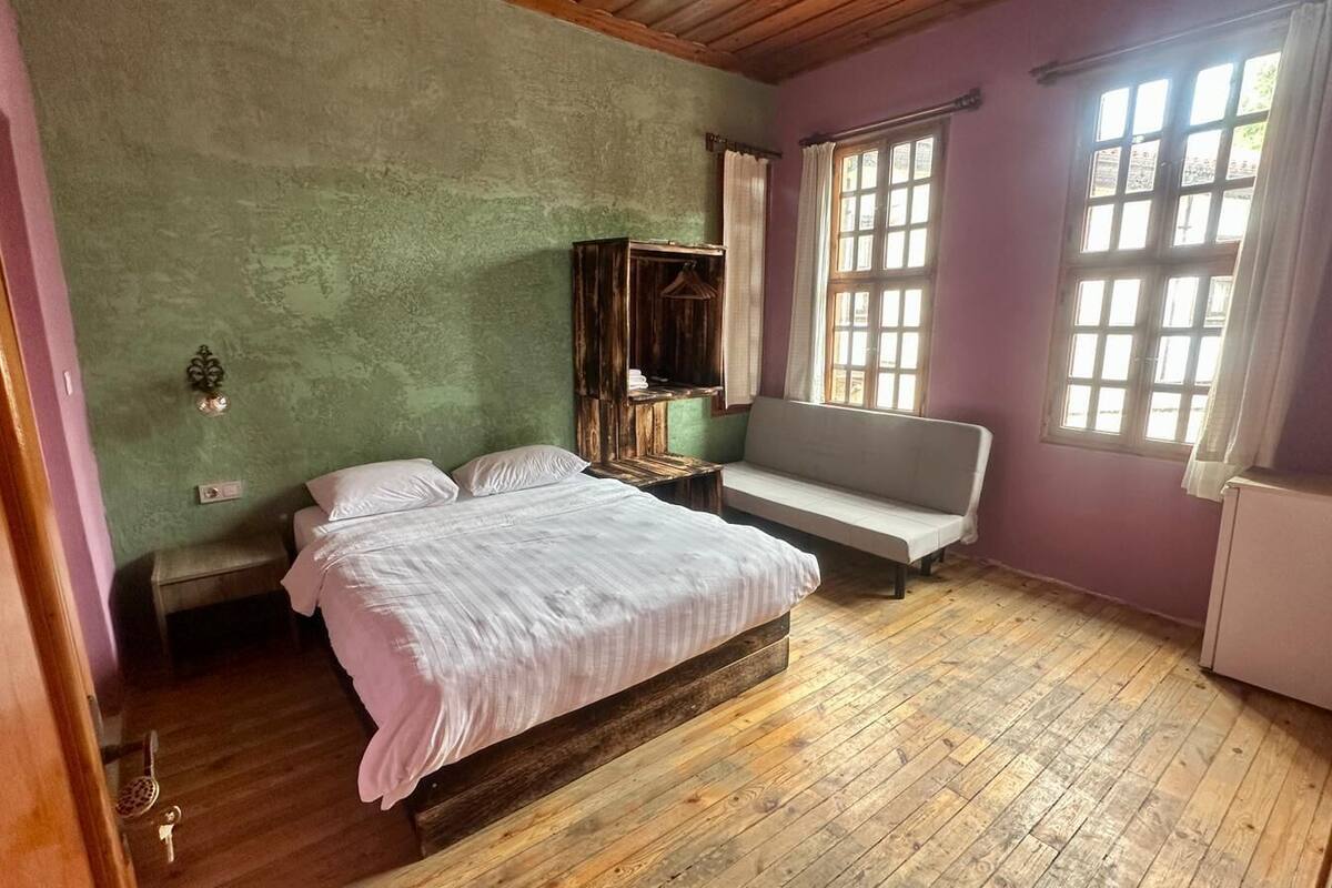 A bedroom with a bed, a bench, a window, and a radiator.