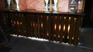 Zona de bar con pared de ladrillo y ventana con cortinas.