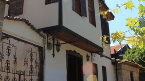 Un edificio de dos pisos con fachada blanca, detalles de madera y techo de tejas.