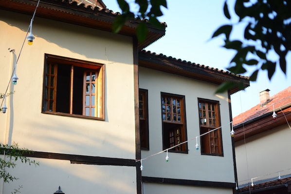 A building with a white facade, wooden window frames, and a tiled roof. - Wood House (Antalya)