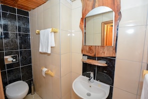 A bathroom with a toilet, sink, mirror, and towel rack. - Wood House (Antalya)