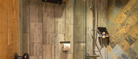 Un baño con inodoro, cabina de ducha de vidrio y pared de madera.